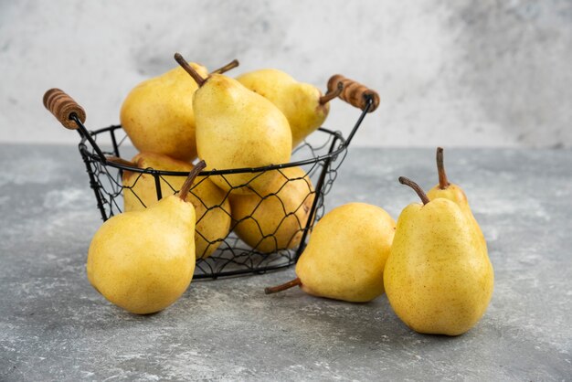 Mazzo di pere gialle fresche in secchio di metallo sulla superficie di marmo.