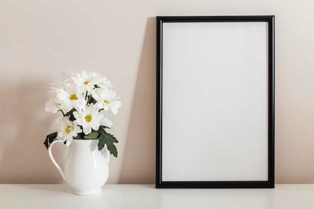 Mazzo di vista frontale di fiori bianchi in un vaso con cornice vuota