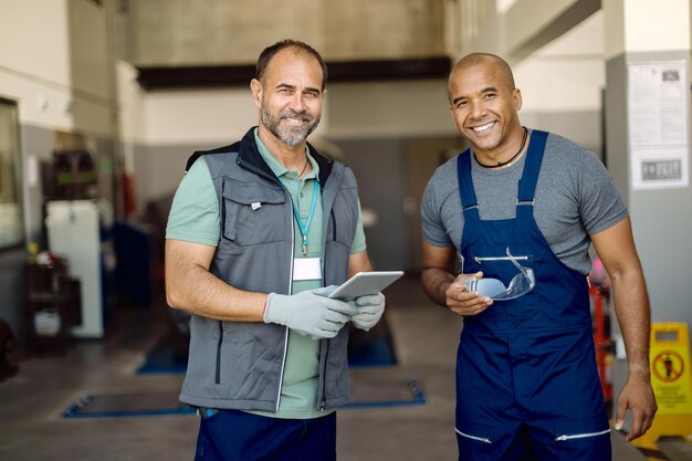 Meccanici di auto felici che lavorano insieme in un'officina