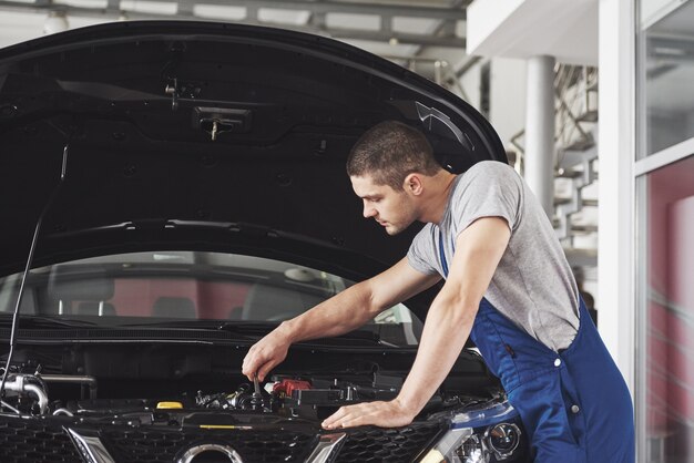 Meccanico auto che lavora in garage. Servizio di riparazione.