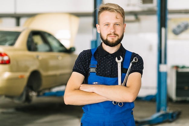 Meccanico auto incrociando le mani con le chiavi