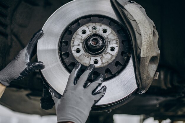 Meccanico che cambia i dischi dei freni nel servizio auto