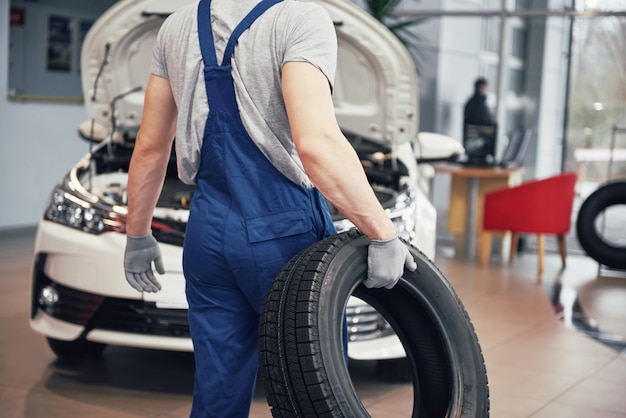 Meccanico che tiene una gomma al garage di riparazione.