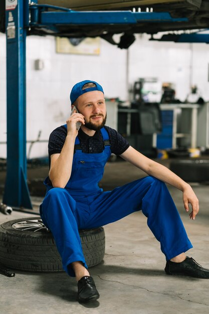 Meccanico che utilizza telefono sulla ruota all&#39;officina