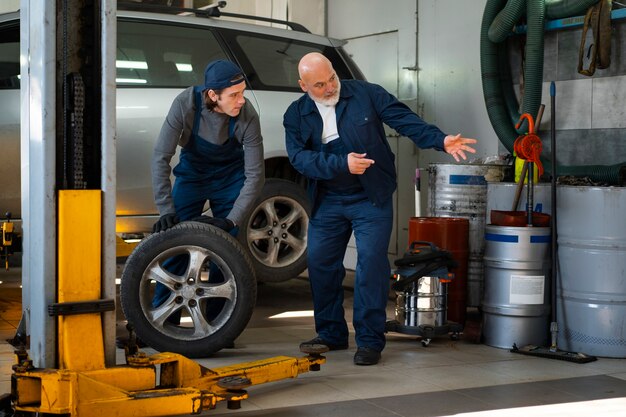 Meccanico di automobile maschio che lavora nell'officina di riparazione dell'automobile