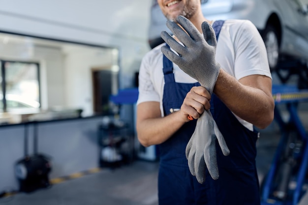 Meccanico irriconoscibile che usa guanti da lavoro in officina