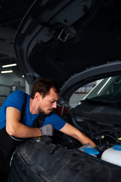 Meccanico maschio che lavora all'auto nell'officina riparazioni auto