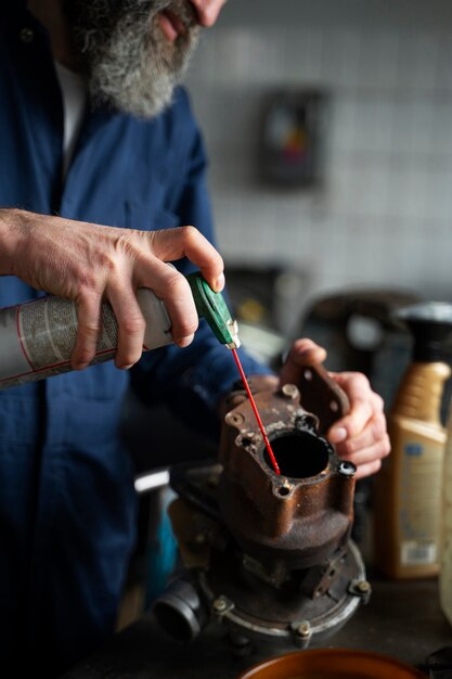 Meccanico maschio che lavora all'auto nell'officina riparazioni auto