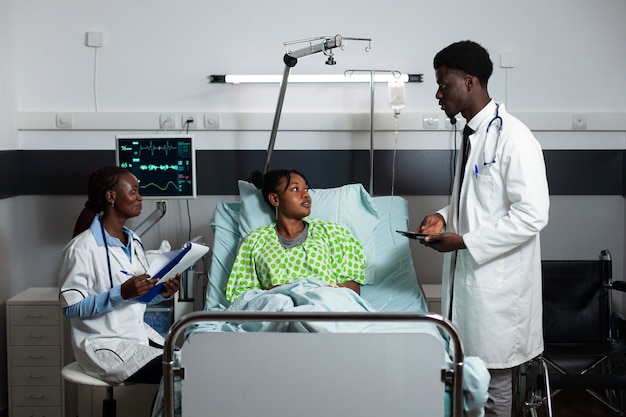 Medici afro che consultano giovani adulti in corsia ospedaliera