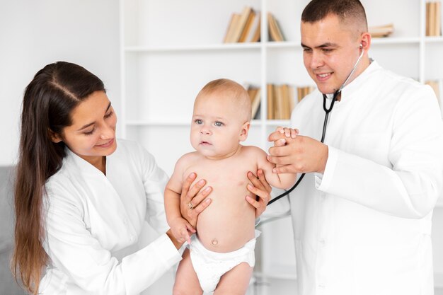 Medici di vista frontale che tengono bambino adorabile