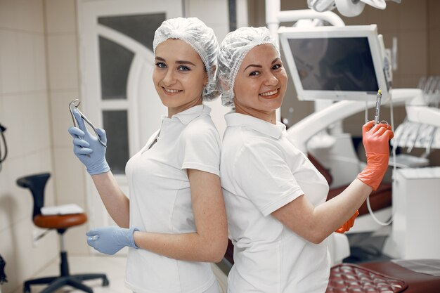 Medici in uniforme speciale, dentisti con i loro strumenti, ragazze guardano la telecamera