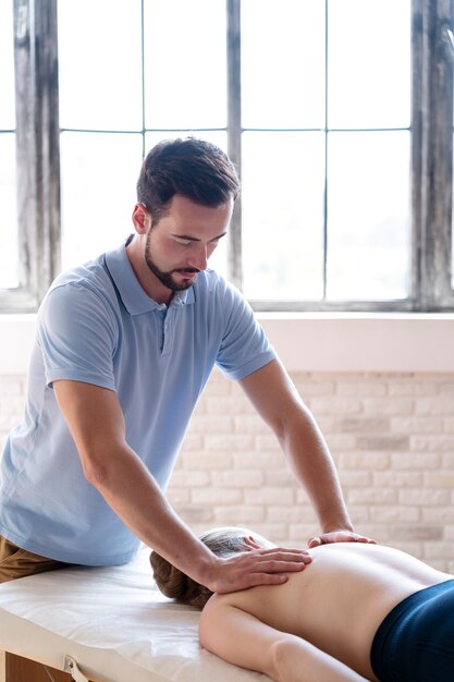 Medico a colpo medio che massaggia la schiena