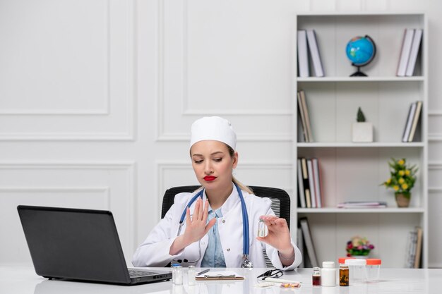 Medico adorabile carino medico in camice bianco e cappello con il computer che spiega online