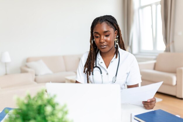 Medico africano dell'oman che parla online con il paziente che effettua una videochiamata guardando la fotocamera giovane donna che indossa uniforme bianca con lo stetoscopio che parla di consulenza e concetto di terapia