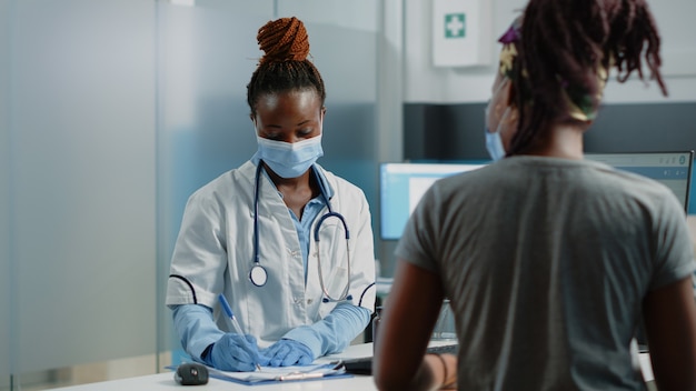 Medico afroamericano che prepara la carta di prescrizione
