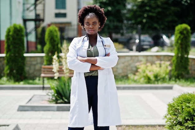 Medico afroamericano femmina al camice con lo stetoscopio all'aperto