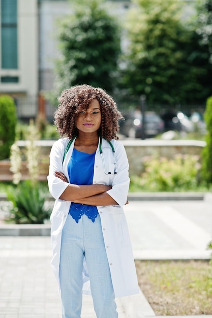 Medico afroamericano femmina al camice con lo stetoscopio all'aperto