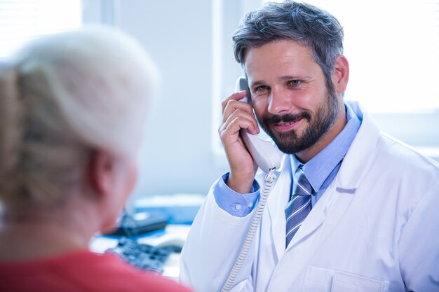 Medico che comunica sul telefono di rete fissa in ufficio medico presso l&#39;ospedale