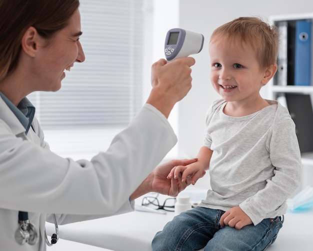 Medico che controlla la temperatura del bambino