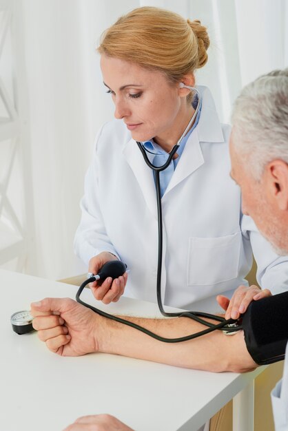 Medico che gonfia il bracciale per la pressione sanguigna