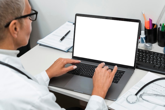 Medico che lavora su un computer portatile in bianco
