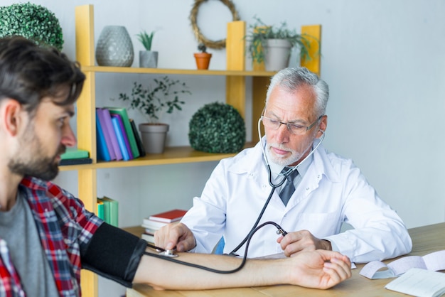 Medico che misura la pressione sanguigna del giovane paziente