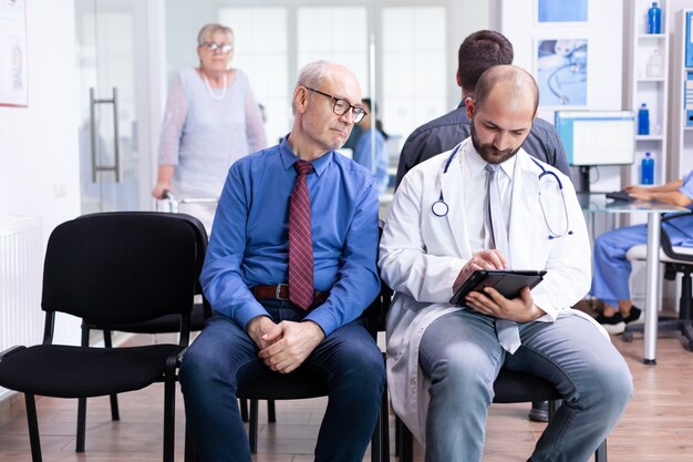 Medico che spiega i risultati del test a un uomo anziano nell'area di attesa dell'ospedale