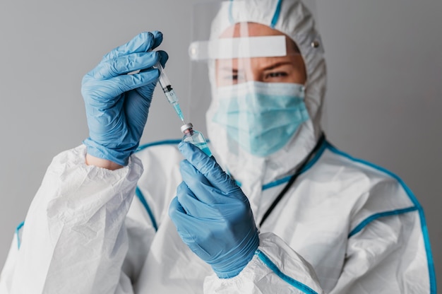 Medico che tiene la preparazione di un vaccino mentre indossa l'equipaggiamento protettivo
