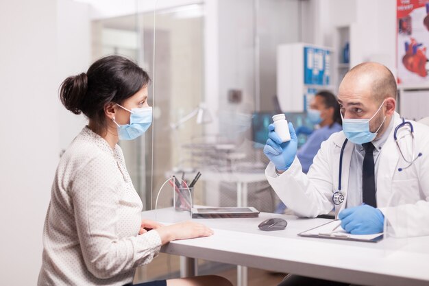 Medico con maschera contro il coronavirus che tiene la bottiglia di pillole per il paziente.