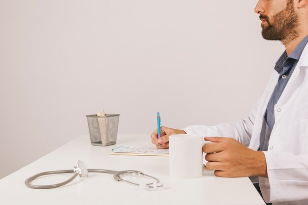 Medico con tazza di caffè che lavora alla sua scrivania