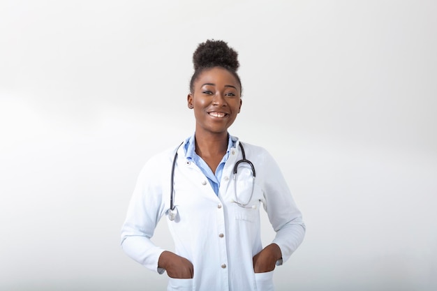 Medico con una mano di stetoscopio in tasca Primo piano di una donna sorridente mentre in piedi dritto su sfondo bianco