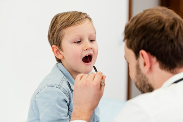 Medico del primo piano che controlla la bocca del bambino