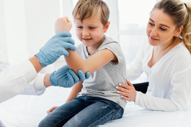 Medico del primo piano che tiene il braccio del bambino