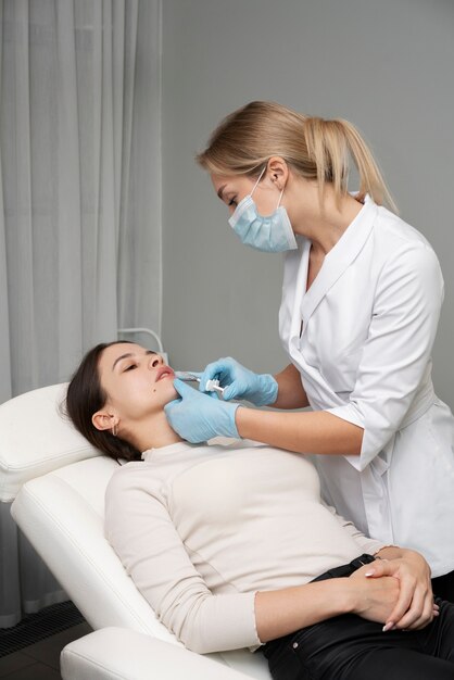 Medico del tiro medio che inietta le labbra