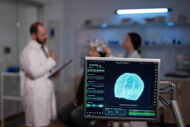 Medico di neuroscienza che tiene appunti che mostra il trattamento contro le malattie del cervello al paziente con auricolare eeg. Donna seduta nel laboratorio scientifico neurologico che tratta le disfunzioni del sistema nervoso.