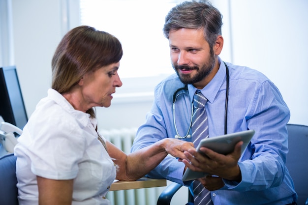 Medico di sesso maschile discutere con il paziente su tavoletta digitale