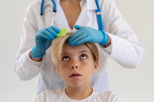Medico di vista frontale che aiuta il ragazzo con i pidocchi