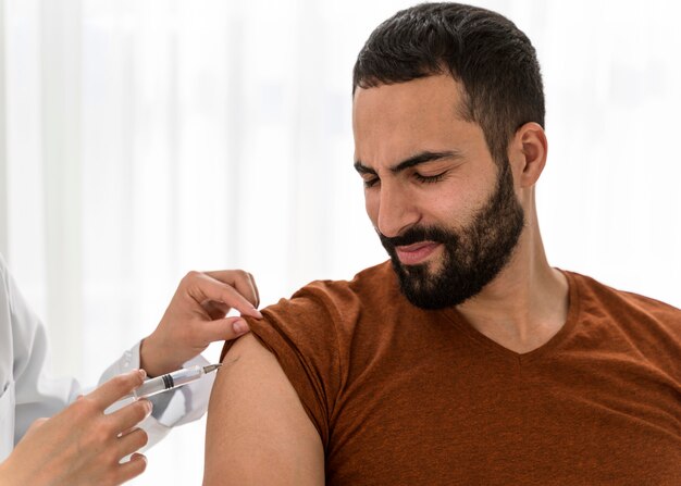 Medico di vista frontale che vaccina un uomo barbuto