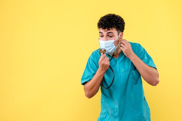 Medico di vista frontale il dottore in maschera guarda il fonendoscopio