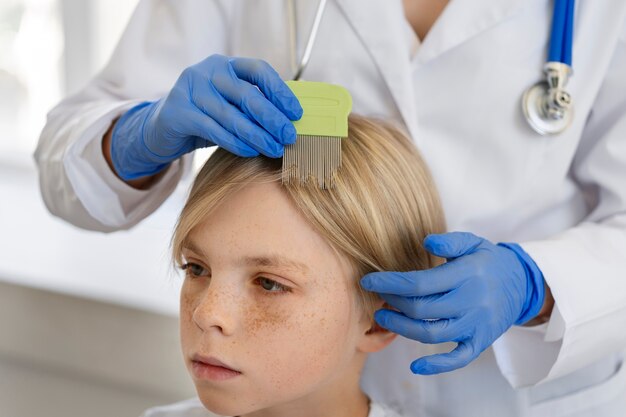 Medico di vista laterale che aiuta il ragazzo con i pidocchi
