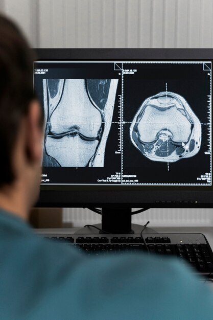 Medico di vista posteriore che esamina le scansioni TC sul computer