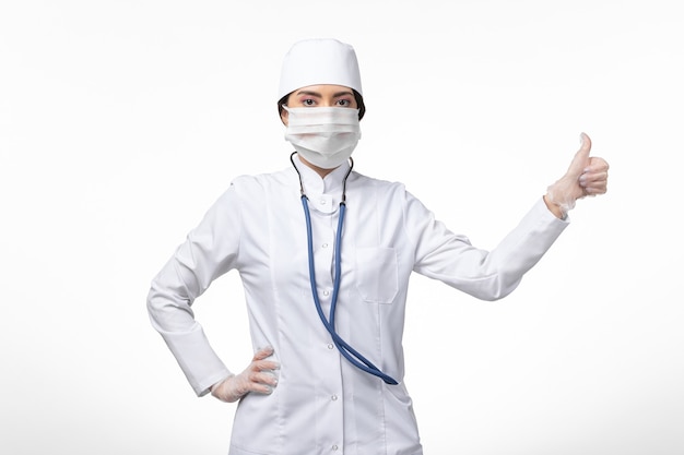 Medico donna vista frontale in tuta medica sterile bianca con maschera a causa di covid- sul muro bianco covid- malattia da virus pandemico