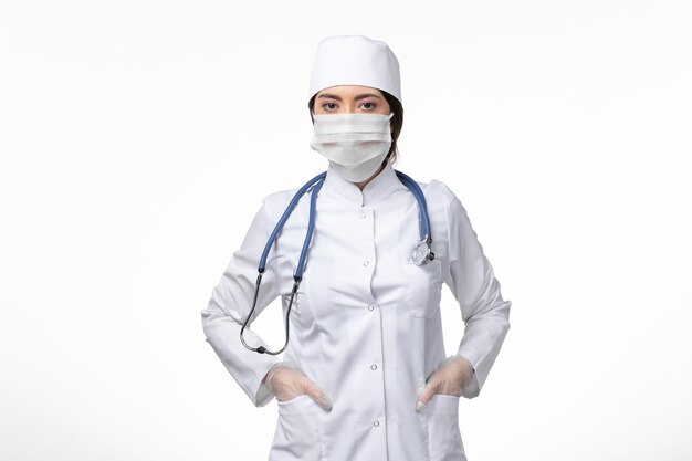 Medico donna vista frontale in tuta medica sterile bianca e maschera da indossare a causa di covid- posa sul muro bianco malattia virus covid- pandemia