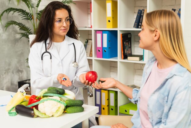 Medico e paziente del colpo medio con la frutta