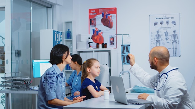 Medico e pazienti che guardano i raggi x seduti in studio medico. Medico specialista in medicina che fornisce consulenza sui servizi di assistenza sanitaria, trattamento radiografico nell'armadio ospedaliero della clinica