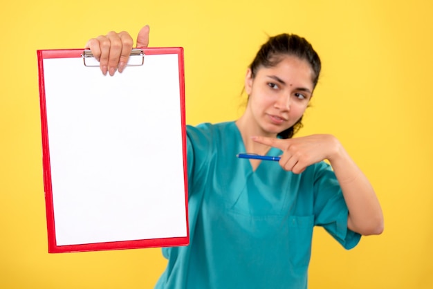 Medico femminile affascinante di vista frontale che indica agli appunti su priorità bassa gialla