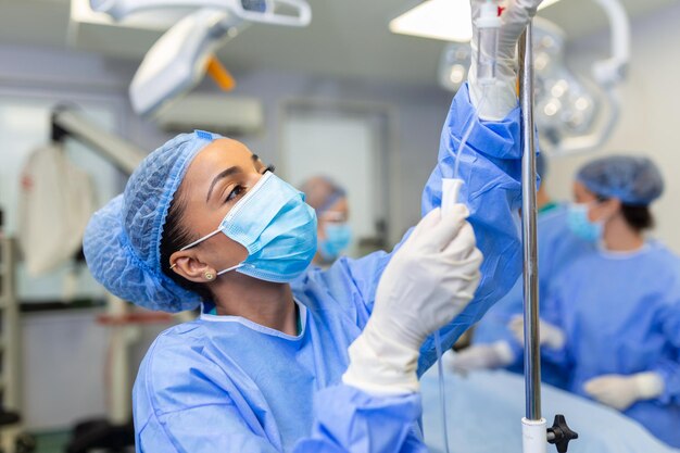 Medico femminile afroamericano in sala operatoria che mette i farmaci attraverso un concetto di chirurgia IV