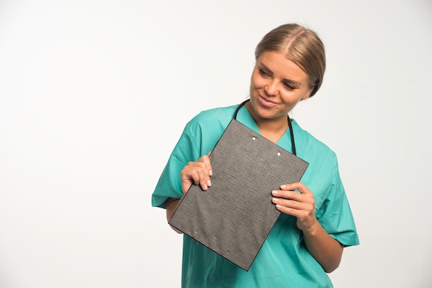 Medico femminile biondo in uniforme blu che tiene un libro di ricevuta e che sorride.