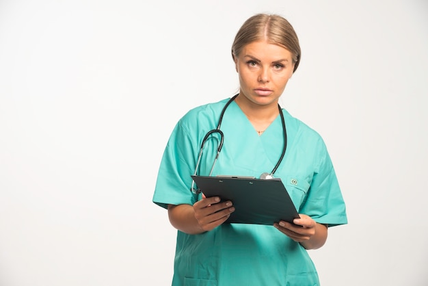 Medico femminile biondo in uniforme blu che tiene un libro di ricevute e sembra premuroso.