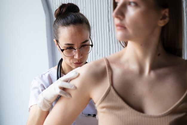 Medico femminile che diagnostica un melanoma sul corpo di una paziente di sesso femminile